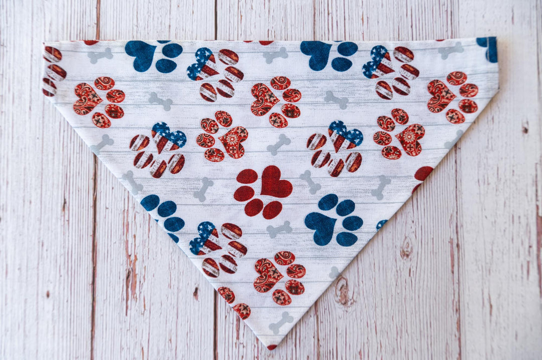  white dog bandana with red white and blue dog paw prints and grey bones