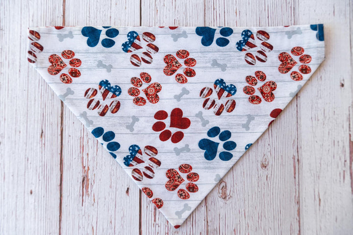  white dog bandana with red white and blue dog paw prints and grey bones